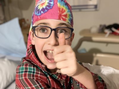 boy giving thumbs up during eeg while wearing a tie dye nillynoggin eeg cap