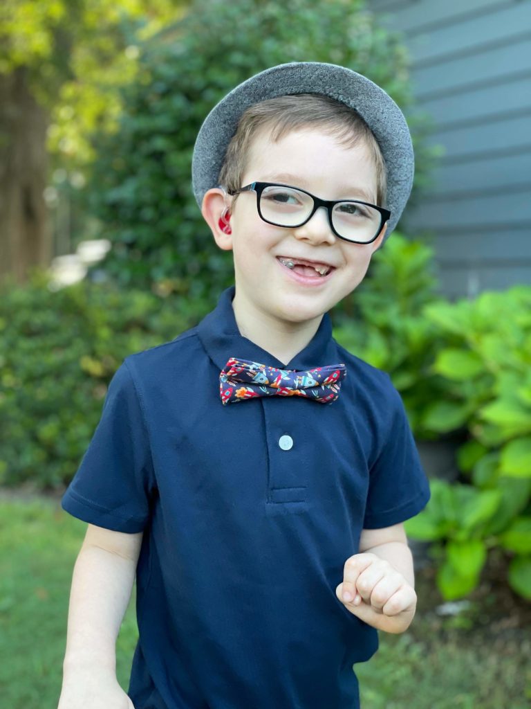 boy smiling wearing a bow tie and glasses